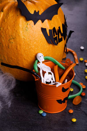 Halloween pumpkin with candles, spiders, web, sweets, horror stories on a dark background, closeup. The concept of autumn holidays.の写真素材