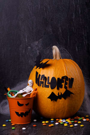 Halloween pumpkin with candles, spiders, web, sweets, horror stories on a dark background, closeup. The concept of autumn holidays.の写真素材