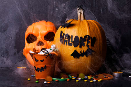 Halloween pumpkin with candles, spiders, web, sweets, horror stories on a dark background, closeup. The concept of autumn holidays.の写真素材