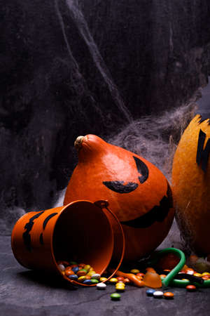 Halloween pumpkin with candles, spiders, web, sweets, horror stories on a dark background, closeup. The concept of autumn holidays.の写真素材