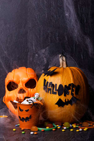 Halloween pumpkin with candles, spiders, web, sweets, horror stories on a dark background, closeup. The concept of autumn holidays.の写真素材