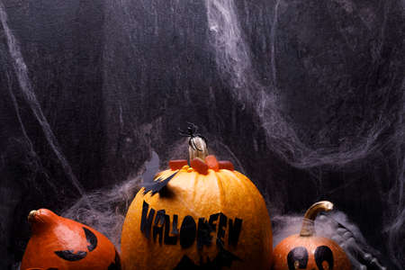 Halloween pumpkin with candles, spiders, web, sweets, horror stories on a dark background, closeup....