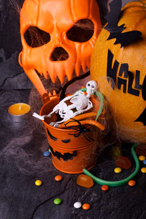 Halloween pumpkin with candles, spiders, web, sweets, horror stories on a dark background, closeup. The concept of autumn holidays.の写真素材