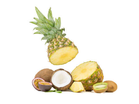 A sliced ripe and tropical pineapple, juicy passion fruit, kiwi and halved coconut pieces isolated on a white background.の写真素材