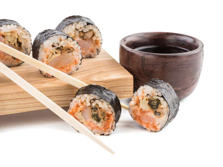 A set of sushi rolls with chopsticks and soy sauce on a wooden board isolated on white background. A concept of seafood and Japanese cuisine.の写真素材