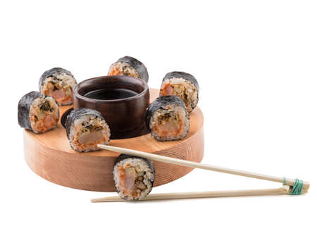 A set of sushi rolls with chopsticks and soy sauce on a round wooden board isolated on white background. A concept of seafood and Japanese cuisine.の写真素材