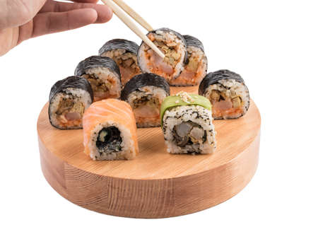 A set of sushi rolls with chopsticks on a round wooden board isolated on white background. A concept of seafood and Japanese cuisine.の写真素材