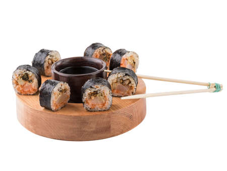 A set of sushi rolls with chopsticks and soy sauce on a round wooden board isolated on white background. A concept of seafood and Japanese cuisine.の写真素材