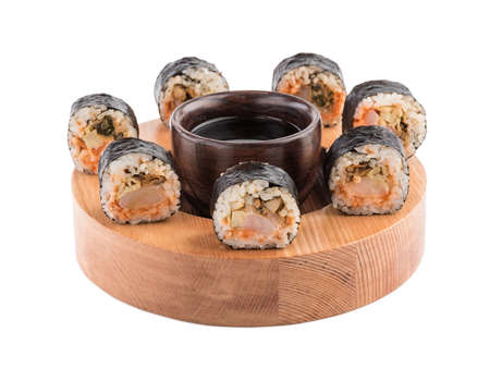 A set of sushi rolls with chopsticks and soy sauce on a round wooden board isolated on white background. A concept of seafood and Japanese cuisine.の写真素材