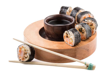 A set of sushi rolls with chopsticks and soy sauce on a round wooden board isolated on white background. A concept of seafood and Japanese cuisine.の写真素材