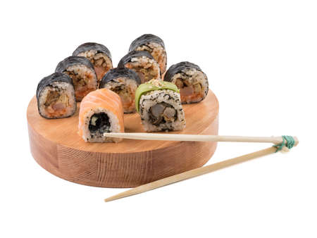 A set of sushi rolls with chopsticks on a round wooden board isolated on white background. A concept of seafood and Japanese cuisine.の写真素材