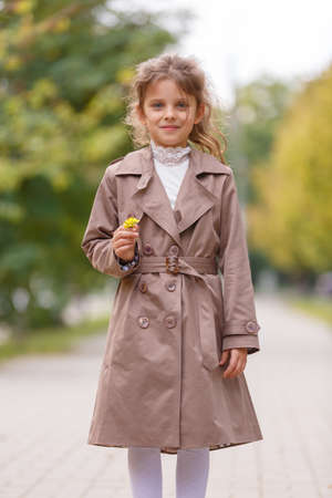 A pretty little girl in an autumn coat in the park. Autumn concept.の写真素材