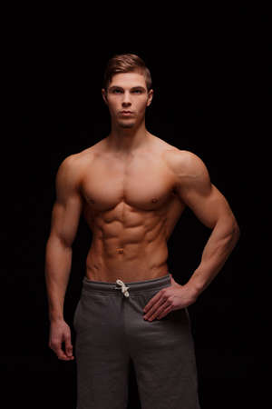 A sexy sportsman with perfect muscles on a black background. Gym, workout, exercising conceptの写真素材