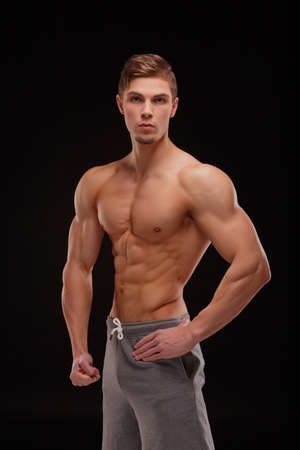 A sexy sportsman with perfect muscles on a black background. Gym, workout, exercising conceptの写真素材