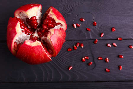 A close-up of a red garnet. Healthy sour pomegranate on a black background. A garnet piece full of juicy, fresh, tasty seeds.の写真素材