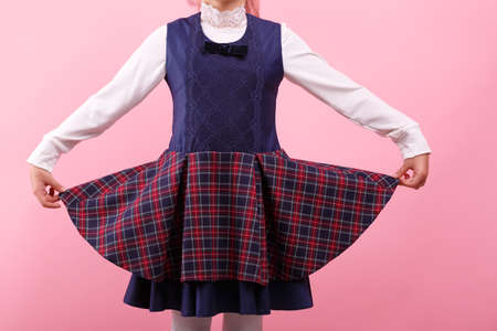 A body of little girl in a school uniform on a bright pink background, close-up. Education, school concept.の写真素材