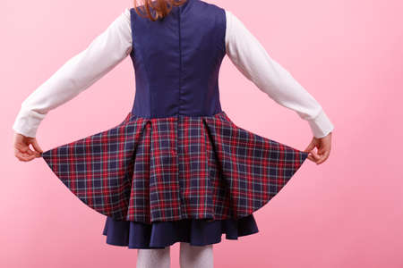 A back of girl in a school uniform on a bright pink background, close-up. Education, school concept.の写真素材