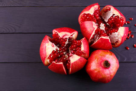 The sweet, fresh and natural garnet for desserts and beverages on a black background. Bright red pomegranate broke down into partsの写真素材