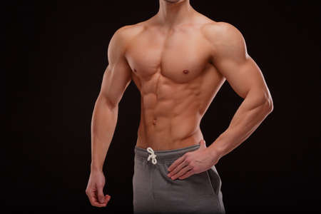 A body of a sexy sportsman with naked muscular torso on a black background. Strong and powerful concept.の写真素材