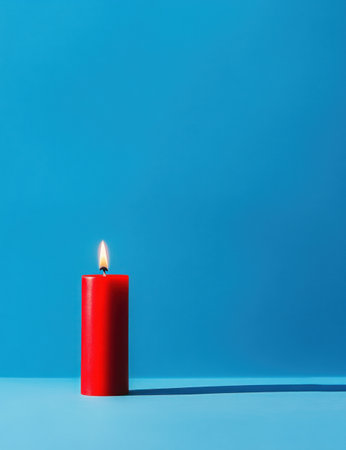A red candle is placed on the left side of an isolated blue background, with its flame burning brightly against the solid color backdrop. The simplicity and minimalism in the composition highlight details such as texture and shape. This photograph features a clean aesthetic with no clutter or elements that extend beyond the candle's body. --ar 23:30 --v 6.1 Job ID: aaa33cb3-6de0-4ec6-936a-33d561d25737の素材