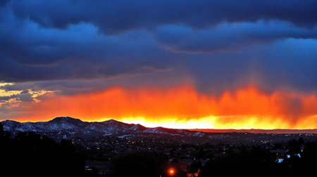 A panoramic view of the silhouette of snowy mountains against an orange and blue sky at sunset, with trees covered in snow on one side of the mountain range. The sky is filled with dramatic clouds, creating a contrast between the warm colors from the setting sun and the cool tones of the winter night. A small light source illuminates part of the forest area. Captured with a Nikon D850 DSLR camera using a Nikkor ultra-wide lens. --chaos 30 --ar 16:9 --v 6.1 Job ID: ddb527ec-11fb-4410-8a50-b96bbe5ab487の素材
