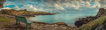 Panoramic view of the bay at Guernsey with a green bench overlooking the cliffs and blue sea. --ar 52:15 --v 6.1 Job ID: b05d280b-d708-431f-80f8-78441e27e414の素材