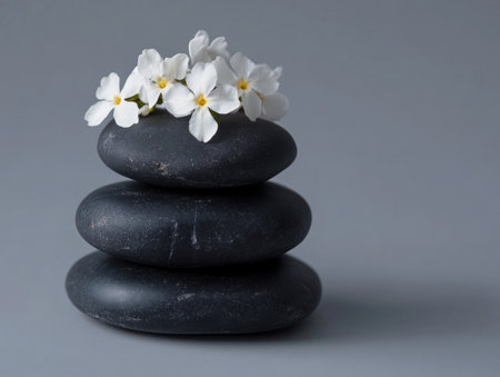 Photo of a stack of black stones with white jasmine flowers on top, isolated on a solid background. --ar 4:3 --v 6.1 Job ID: 50636eb7-32df-47b7-b356-16560bb0d4acの素材