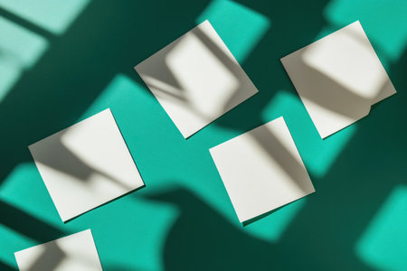Flat lay of blank white cards on a green and teal background with a shadow overlay, creating geometric shadows. --ar 3:2 --v 6.1 Job ID: a9deeef0-e7cf-4cb4-b30e-60a312d468faの素材
