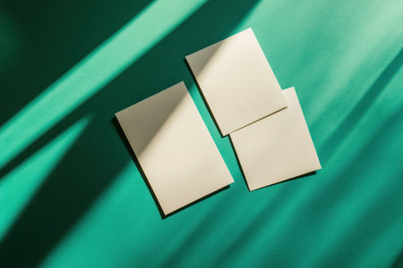 Flat lay of blank white cards on a green and teal background with a shadow overlay, creating geometric shadows. --ar 3:2 --v 6.1 Job ID: a9deeef0-e7cf-4cb4-b30e-60a312d468faの素材