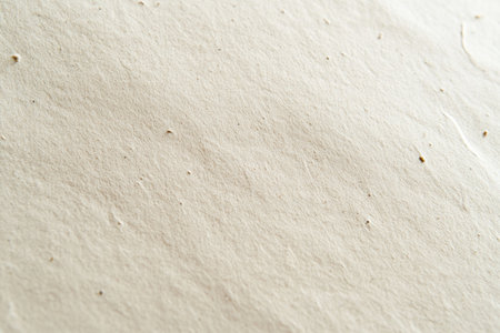 A close-up of the texture on light beige kraft paper, emphasizing its natural and soft appearance with subtle ink marks scattered across it. The background is plain white to highlight the intricate details in the paper's surface. --ar 3:2 --v 6.1 Job ID: 2043fa75-ec02-4b8b-8ff9-dd6cd7266795の素材
