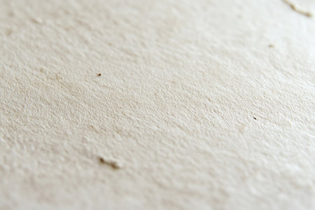 A close-up of the texture on light beige kraft paper, emphasizing its natural and soft appearance with subtle ink marks scattered across it. The background is plain white to highlight the intricate details in the paper's surface. --ar 3:2 --v 6.1 Job ID: 95fbb3f3-d547-41e5-95c9-468d9d30c651の素材
