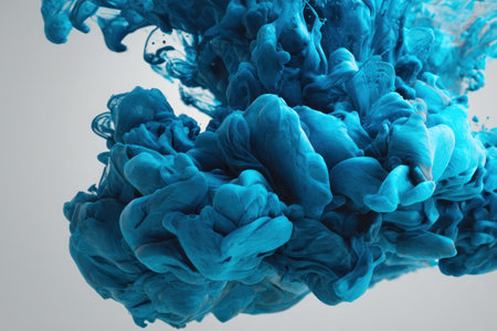 An artistic image presents a vibrant cloud of blue ink suspended in liquid. The swirling forms showcase intricate textures and a dynamic composition. The high-key lighting illuminates the abstract forms against a plain, neutral backdrop. Suitable for artistic projects, design elements, or illustrating concepts of creativity.の素材