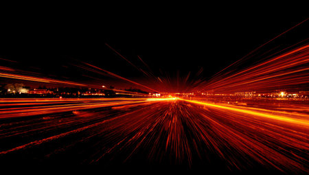 An abstract image featuring vibrant orange and red light trails against a dark background, possibly representing movement or speed. The composition suggests a sense of depth, with light streaks converging towards a central point. The visual style could be used for various commercial or artistic purposes related to technology, energy or transportation.の素材