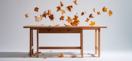 An image showcases a wooden table with falling autumn leaves. The composition features warm tones, soft lighting, and a clear, uncluttered background. This scene creates a sense of seasonal transition. Suitable for various design projects, it could be used in advertising, or editorial content.の素材