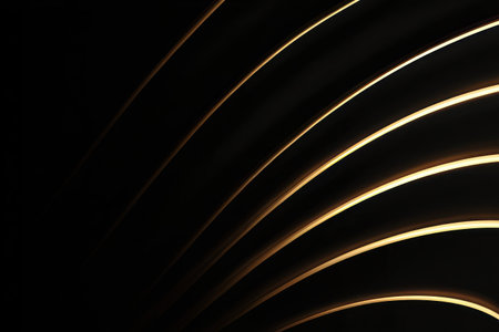 This image presents abstract golden lines against a dark background. The composition uses curved lines and highlights to create a sense of depth and movement. It could be used for various design purposes, including website backgrounds, presentations, or as a visual element in marketing materials.の素材
