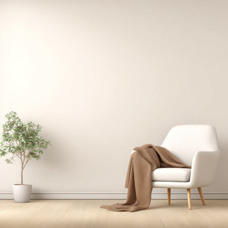 An interior scene features a white armchair draped with a brown blanket, set against a neutral wall. A small potted plant stands nearby on a wooden floor, bathed in soft lighting. This composition offers copy space and is suitable for various commercial applications, including home decor and lifestyle concepts.の素材