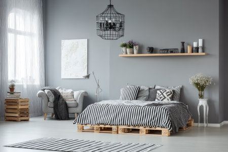 Modern bedroom with gray walls, pallet bed, armchair, art, plants, and striped accentsの素材