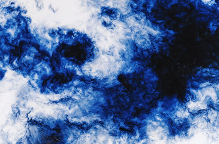 Abstract image of blue ink swirling against a white background, creating smoky patternsの素材