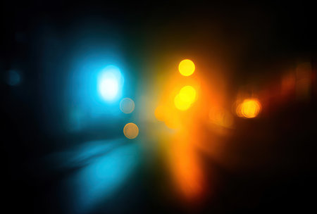 Abstract shot, with a dark backdrop, of blurred bright blue and orange light flaresの素材