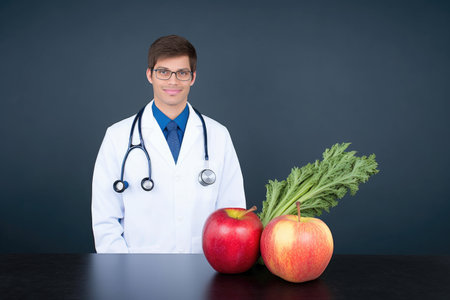 studio shot of a handsome suited young doctor holding up an apple and apple slices, created with generative aiの素材