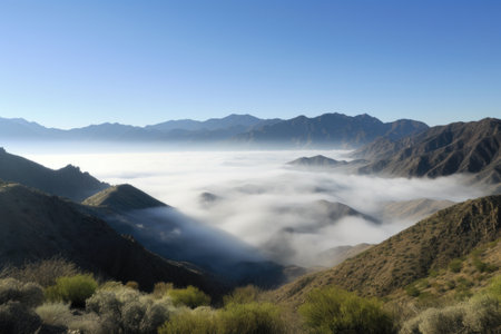 panoramic view of mist-shrouded mountains, bordered by a blue sky, created with generative aiの素材