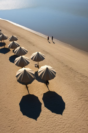 beach umbrellas casting shadows on the sand near water, created with generative aiの素材