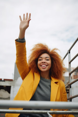 shot of a young woman looking happy while waving from the rooftop of a building under construction, created with generative aiの素材
