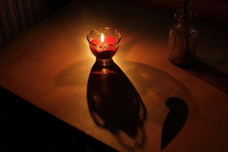 a lit, heart-shaped candle casting a shadow on a table, created with generative aiの素材