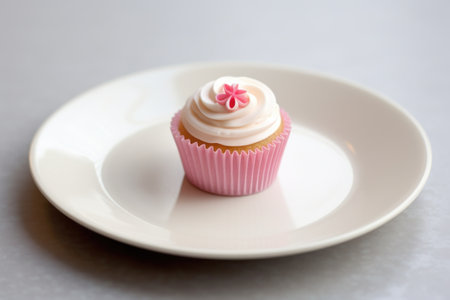 a white plate with a single tiny pink cupcake, created with generative aiの素材