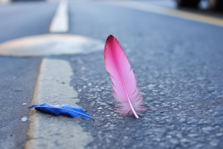 blue feather fallen next to a crushed pink lipstick on a cold pavement, created with generative aiの素材