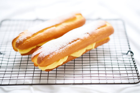 eclair on cooling rack with powdered sugar dustingの素材