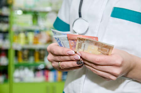 pharmacist woman holding euro biils at the pharmacyの写真素材