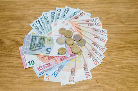 Top view of Euro coins and banknotes on wooden tableの写真素材