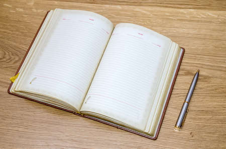 top view of old open book with fountain pen on wooden table